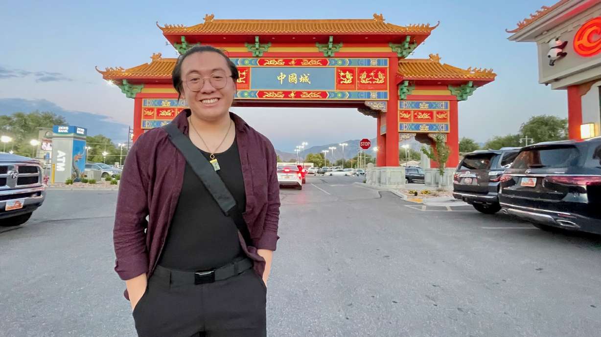 A person stands in a parking lot before a traditional Chinese gate during a community exploration.
